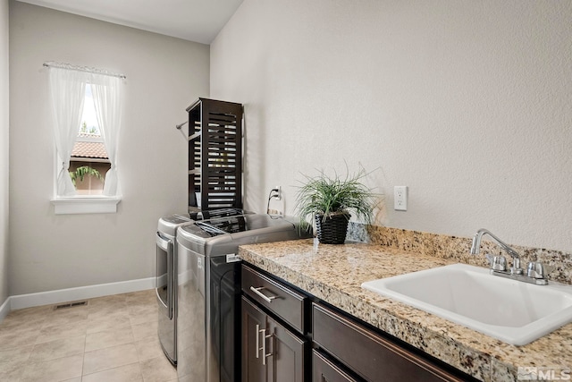 laundry area featuring cabinet space, visible vents, a sink, separate washer and dryer, and baseboards