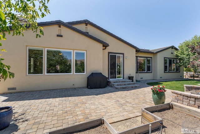 back of house featuring a patio, a tile roof, visible vents, and stucco siding