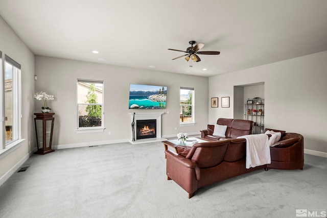 living room featuring recessed lighting, light colored carpet, visible vents, a lit fireplace, and baseboards