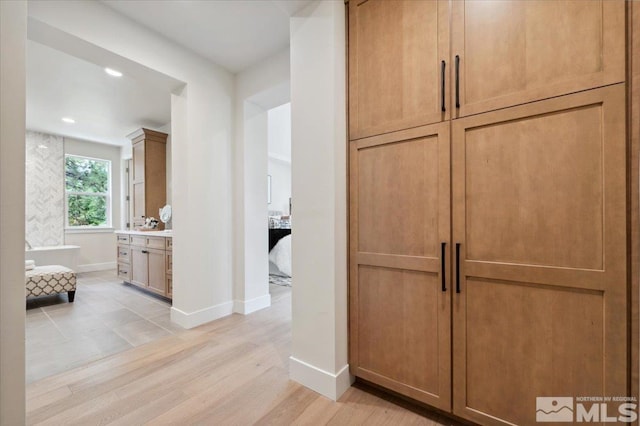 interior space with vanity, wood-type flooring, and a tub to relax in