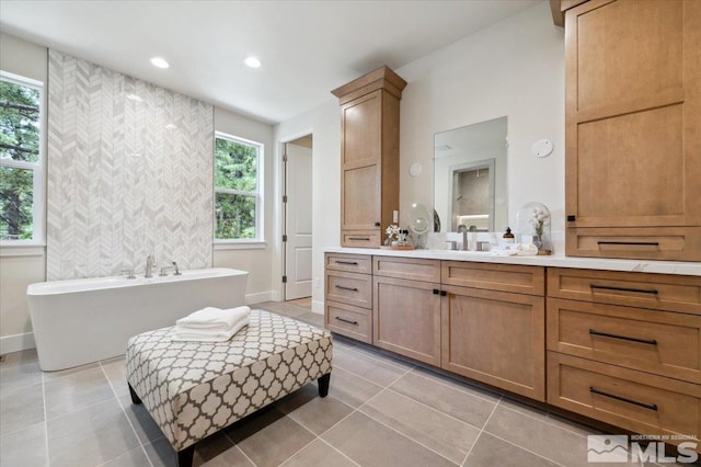 bathroom featuring tile patterned flooring, vanity, and a washtub