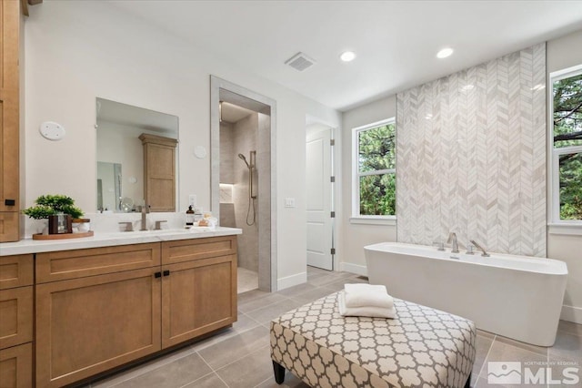 bathroom with tile patterned floors, vanity, and plus walk in shower