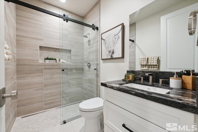 bathroom featuring tile patterned floors, vanity, toilet, and a shower with door