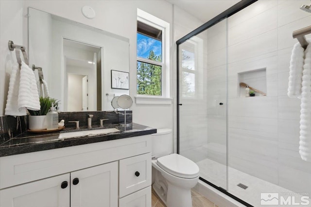 bathroom with vanity, a shower with shower door, and toilet