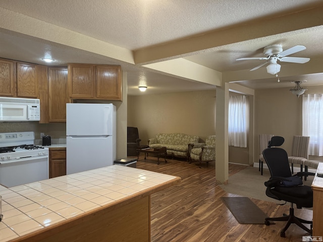 kitchen featuring tile countertops, white appliances, dark hardwood / wood-style floors, ceiling fan, and a textured ceiling