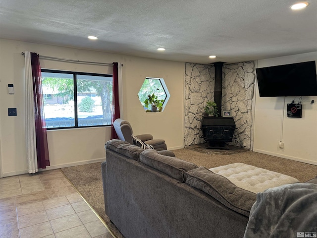 living room with light tile patterned flooring, a wood stove, and a textured ceiling