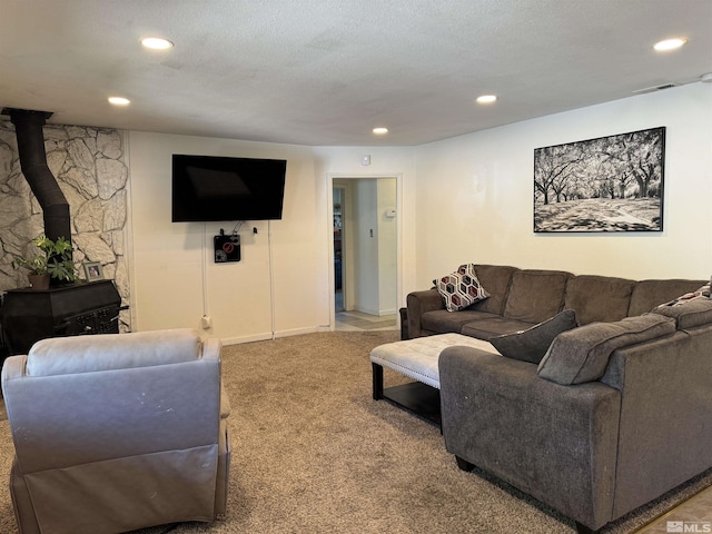 carpeted living room featuring a textured ceiling and a wood stove