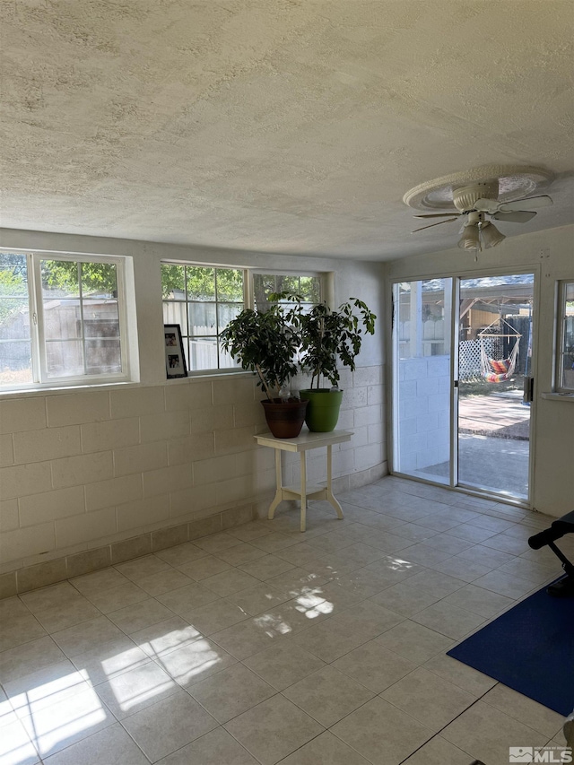 unfurnished sunroom with ceiling fan