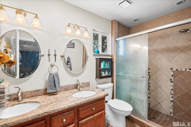 bathroom with double sink vanity, toilet, and an enclosed shower