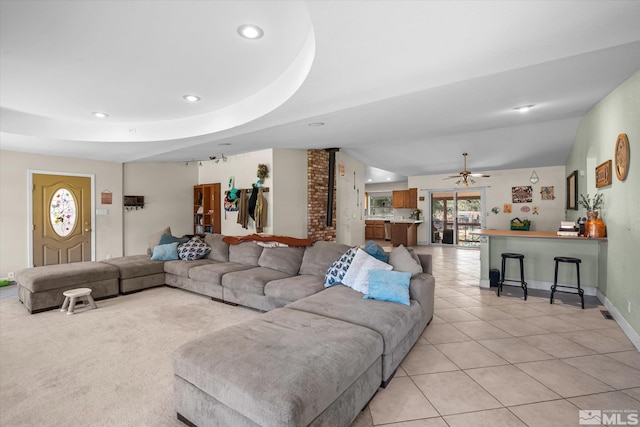 living room with brick wall, light tile patterned floors, ceiling fan, and a tray ceiling