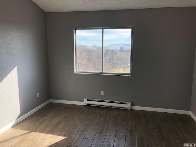 empty room featuring a baseboard radiator, a mountain view, hardwood / wood-style floors, and a wealth of natural light