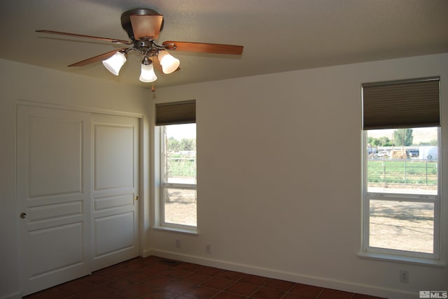 tiled spare room with ceiling fan