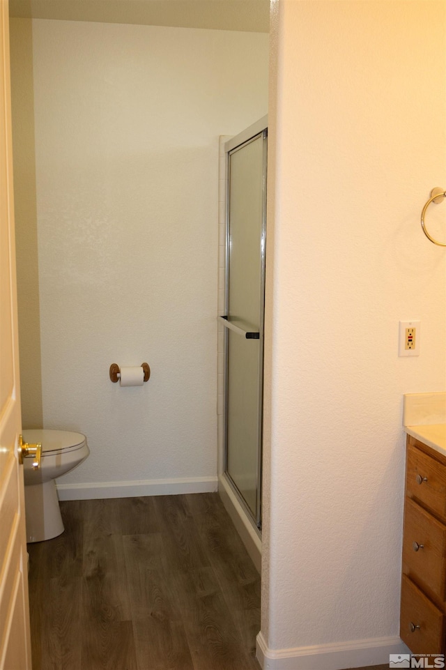 bathroom featuring toilet, an enclosed shower, wood-type flooring, and vanity