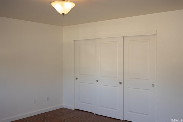 unfurnished bedroom with dark tile patterned flooring and a closet