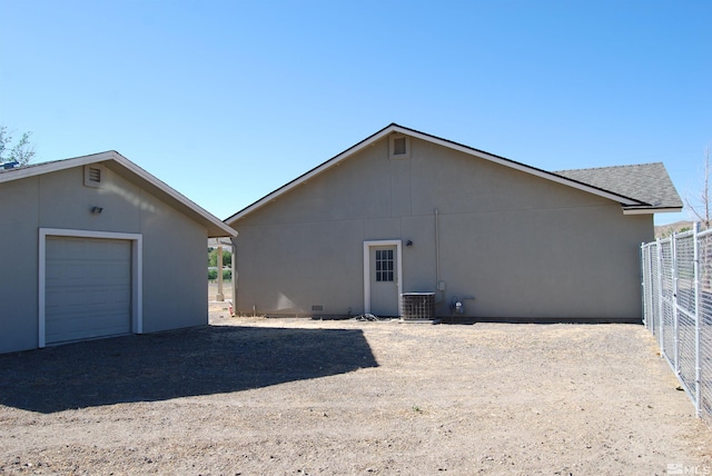 rear view of property featuring central air condition unit, an outbuilding, and a garage