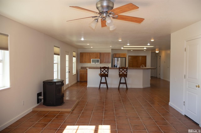 kitchen featuring ceiling fan, a center island, stainless steel fridge, a breakfast bar, and dark tile patterned flooring