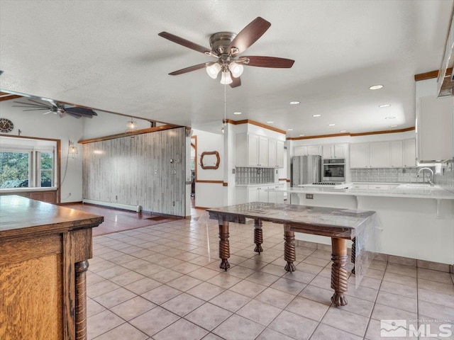 kitchen featuring sink, light tile patterned floors, kitchen peninsula, decorative backsplash, and white cabinets