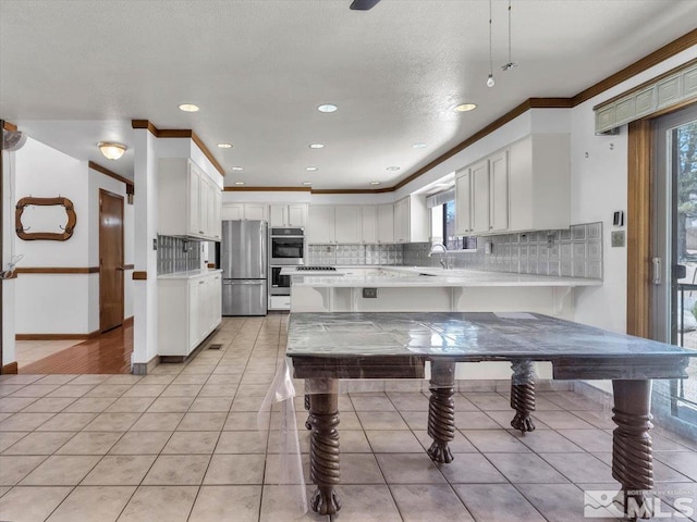 kitchen with backsplash, kitchen peninsula, stainless steel fridge, light tile patterned floors, and white cabinetry