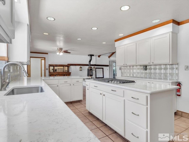 kitchen featuring kitchen peninsula, ceiling fan, sink, white cabinetry, and stainless steel gas stovetop