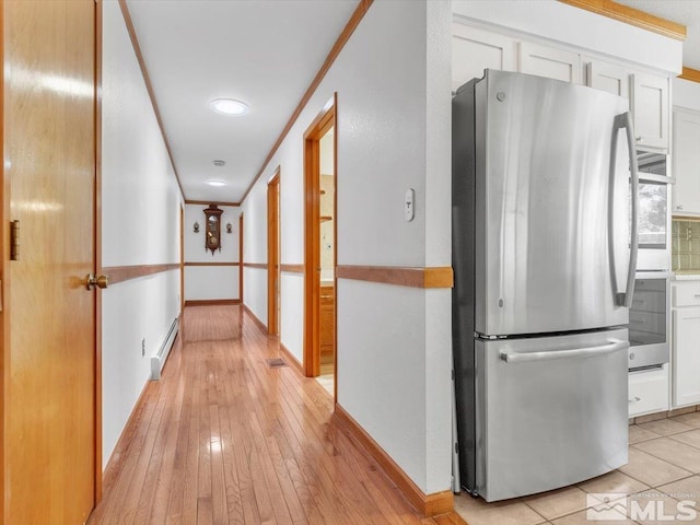 hall with light hardwood / wood-style flooring, a baseboard radiator, and ornamental molding