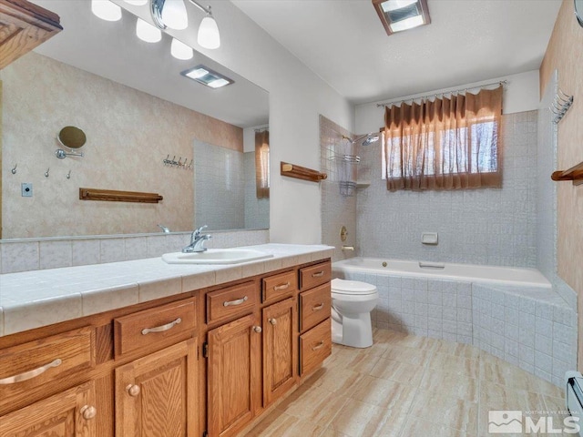 full bathroom featuring vanity, toilet, baseboard heating, and tiled shower / bath combo