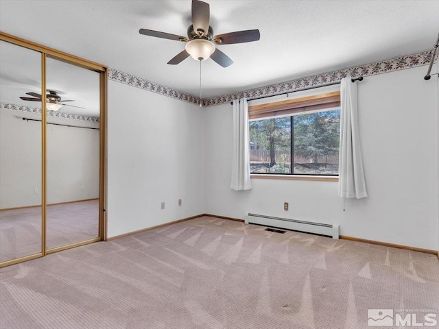 empty room with ceiling fan, light carpet, and a baseboard heating unit