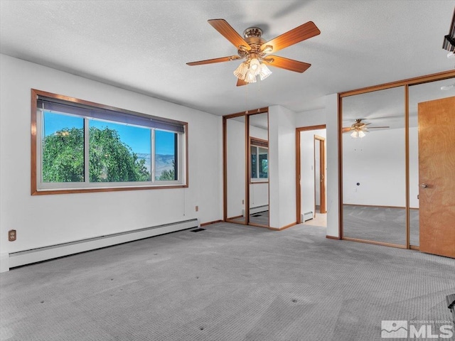 empty room with light colored carpet, a baseboard radiator, and a textured ceiling