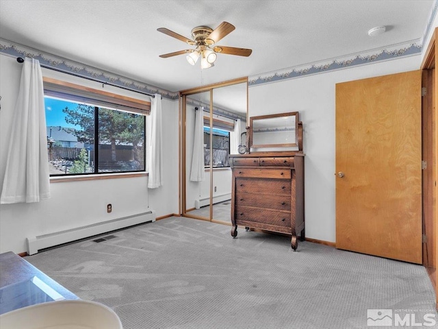 unfurnished bedroom with ceiling fan, a closet, light colored carpet, and a baseboard heating unit