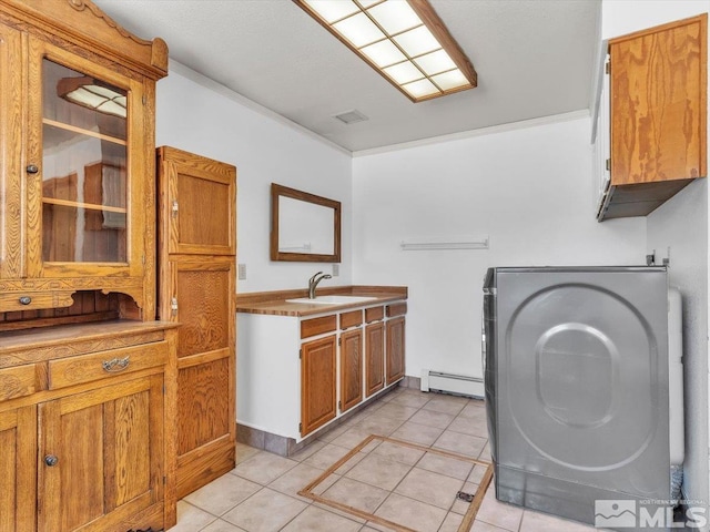 clothes washing area featuring cabinets, a baseboard heating unit, sink, light tile patterned floors, and washer / clothes dryer