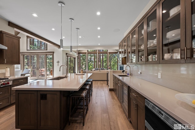 kitchen with sink, a kitchen island with sink, light hardwood / wood-style floors, and decorative light fixtures