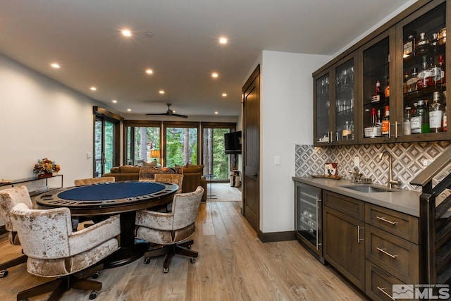 interior space featuring dark brown cabinetry, sink, backsplash, and light wood-type flooring