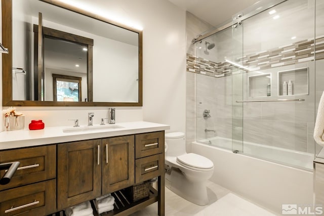 full bathroom with bath / shower combo with glass door, vanity, and toilet