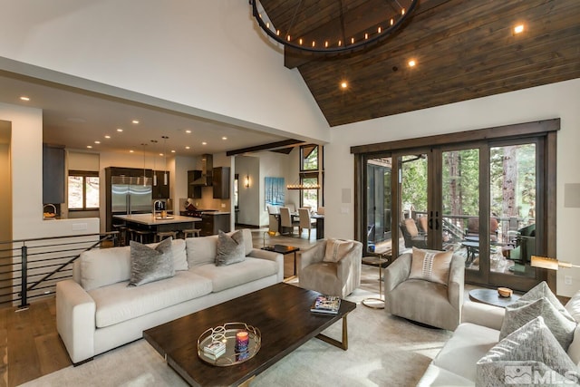 living room with french doors, plenty of natural light, high vaulted ceiling, and light wood-type flooring