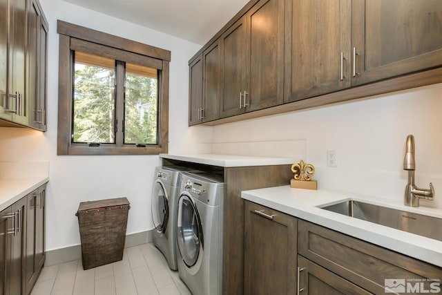 clothes washing area with cabinets, sink, and washer and dryer