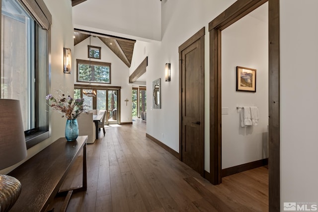 hallway featuring beamed ceiling, hardwood / wood-style flooring, and high vaulted ceiling