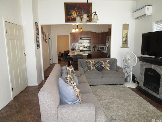 living room with a chandelier, a stone fireplace, and a wall mounted AC