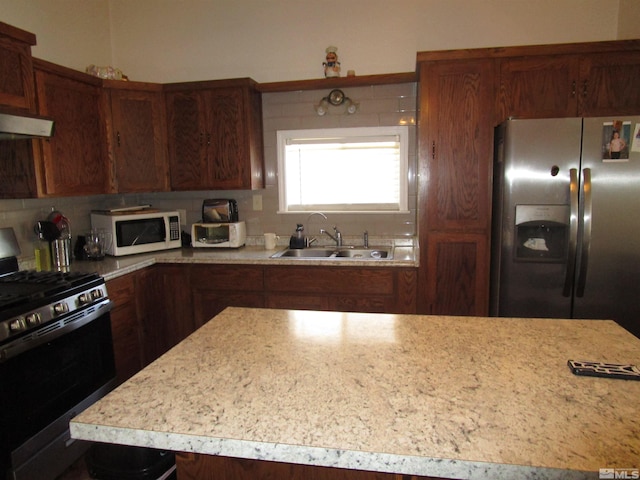 kitchen with a sink, gas range oven, stainless steel fridge, light countertops, and white microwave