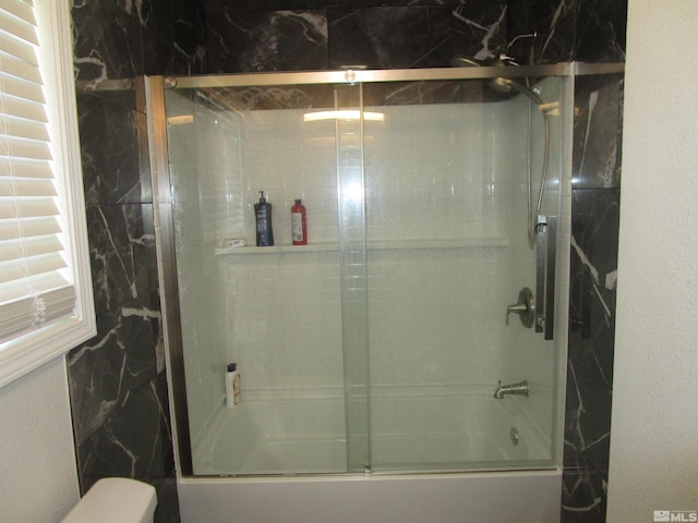 full bathroom featuring combined bath / shower with glass door and toilet