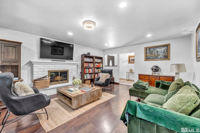 living room with a stone fireplace and dark hardwood / wood-style flooring