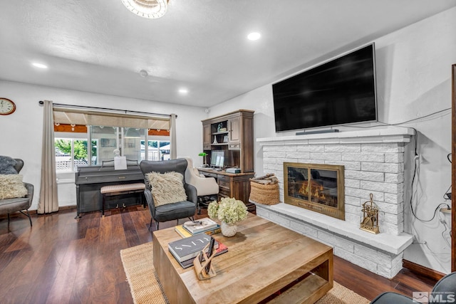 living room with dark wood-type flooring, a textured ceiling, and a fireplace