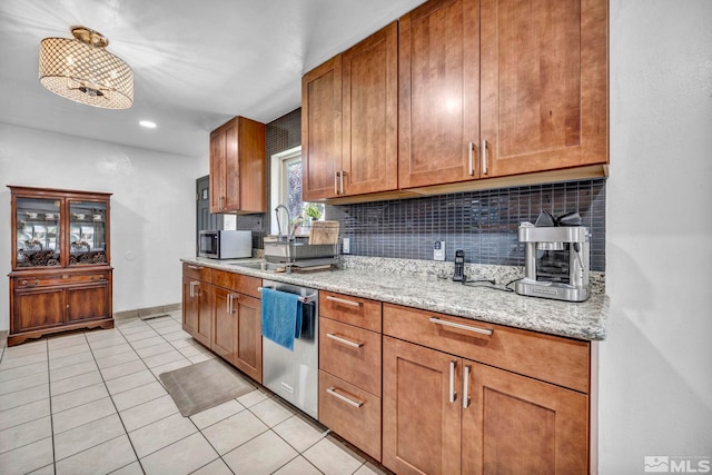 kitchen with light tile patterned flooring, appliances with stainless steel finishes, sink, decorative backsplash, and light stone countertops