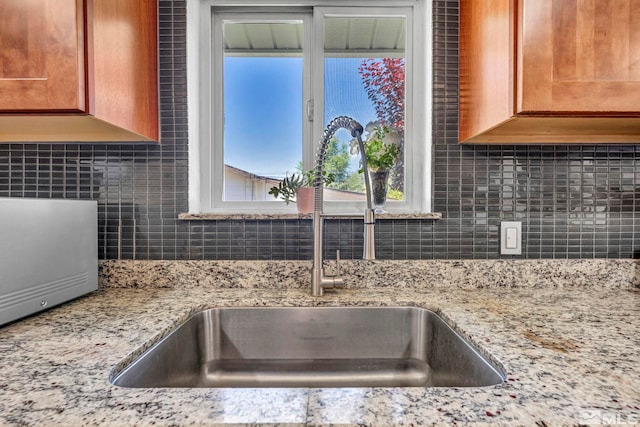 interior details featuring light stone countertops, sink, and decorative backsplash