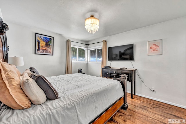 bedroom with wood-type flooring and a notable chandelier