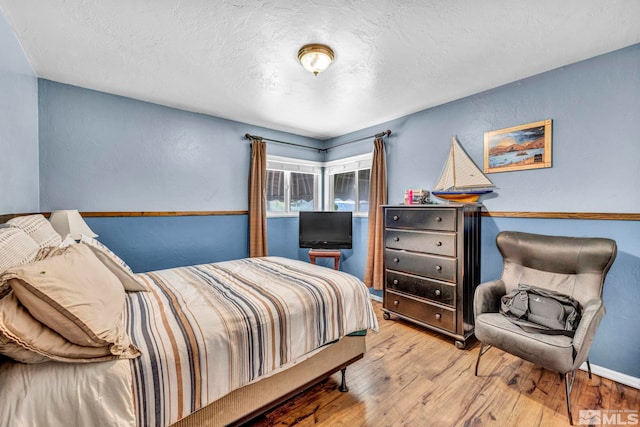 bedroom with a textured ceiling and light wood-type flooring