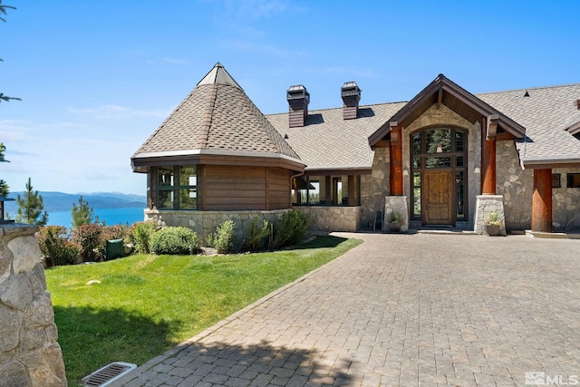 view of front of house with a water view and a front lawn