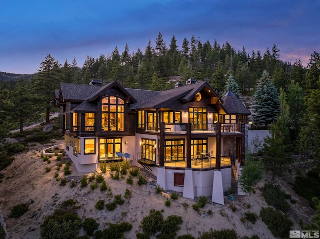 back house at dusk with a balcony