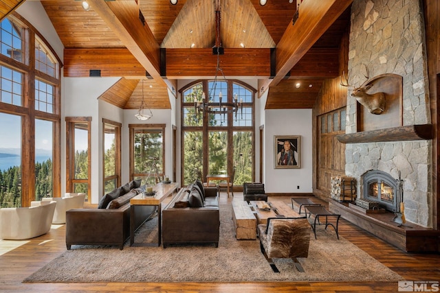 living room with hardwood / wood-style floors, wood ceiling, a stone fireplace, beam ceiling, and high vaulted ceiling