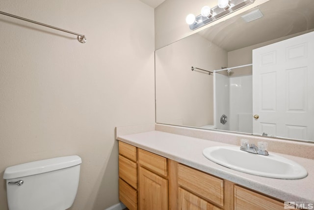 bathroom with toilet, vanity, and walk in shower