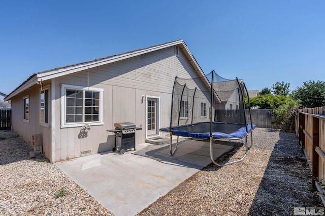 back of property featuring a patio area and a trampoline