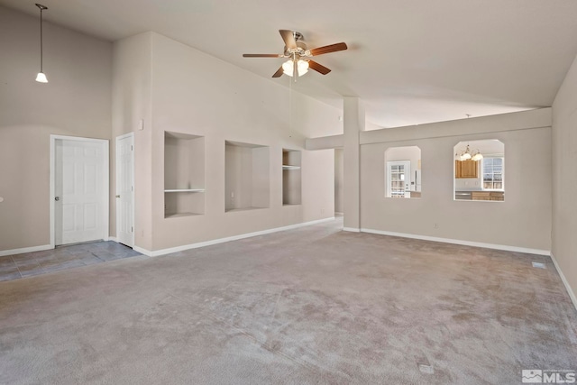 unfurnished living room featuring built in features, ceiling fan with notable chandelier, carpet flooring, and high vaulted ceiling